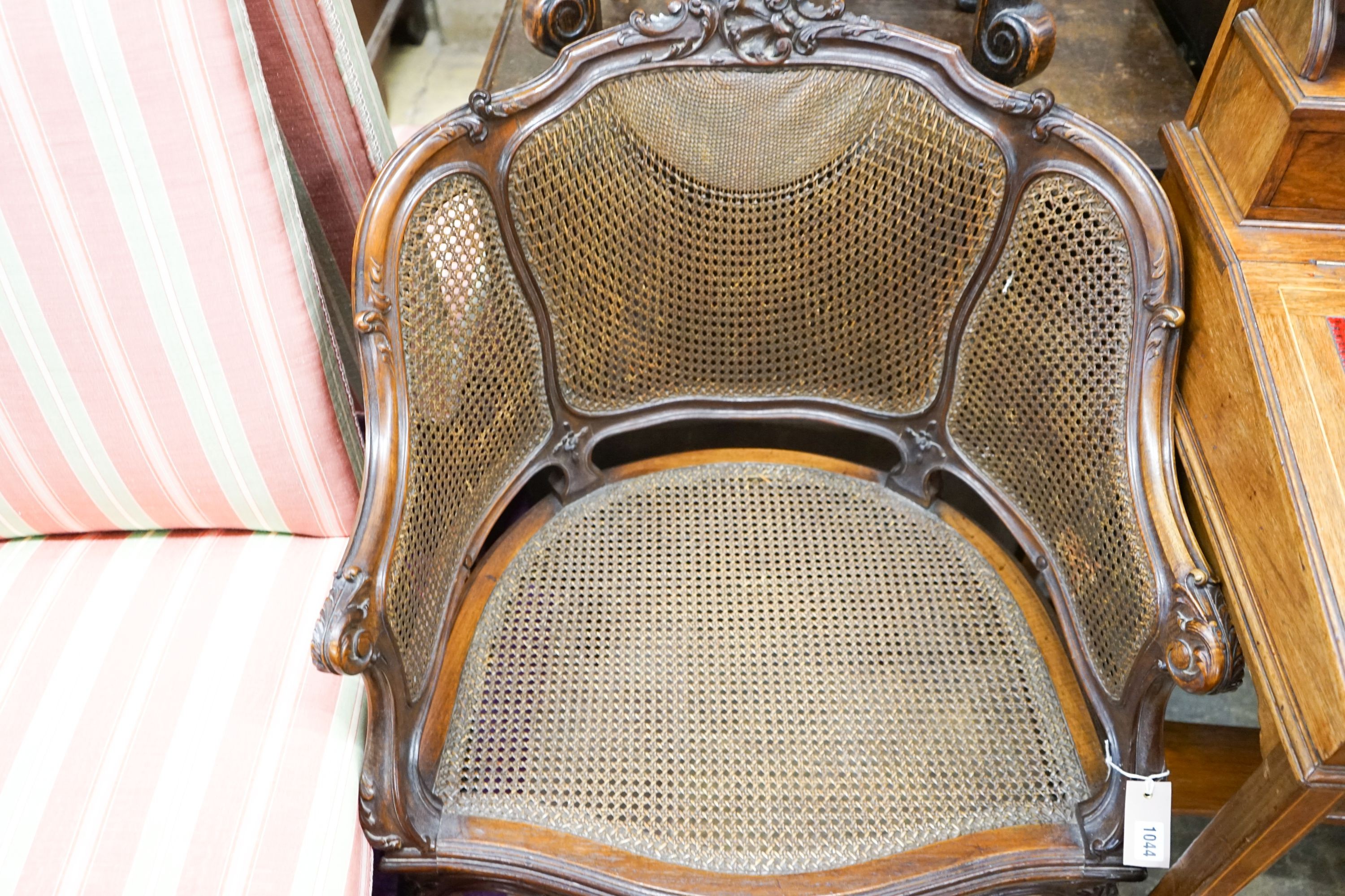 A French style carved walnut frame bergere with caned panels on cabriole legs, length 70cm, depth 52cm, height 86cm together with a Carolean style caned stool